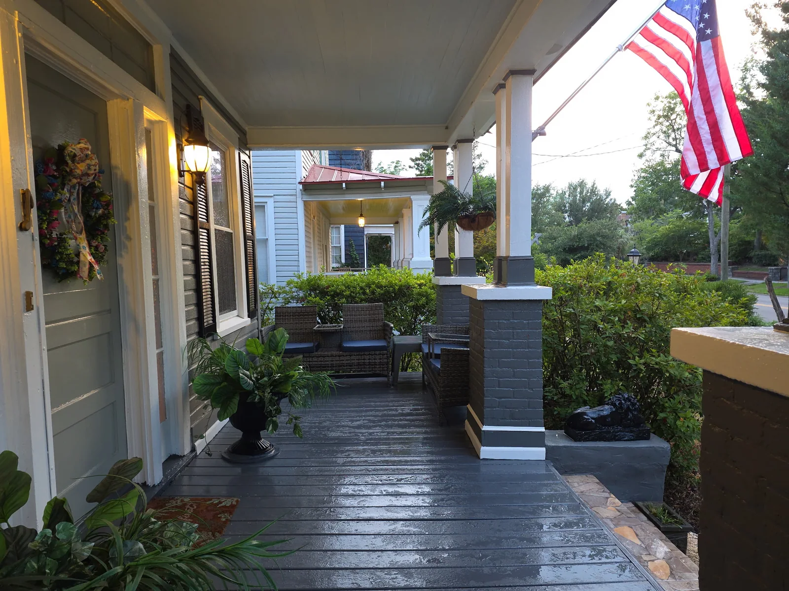 Wide covered front porch with seating and an American flag